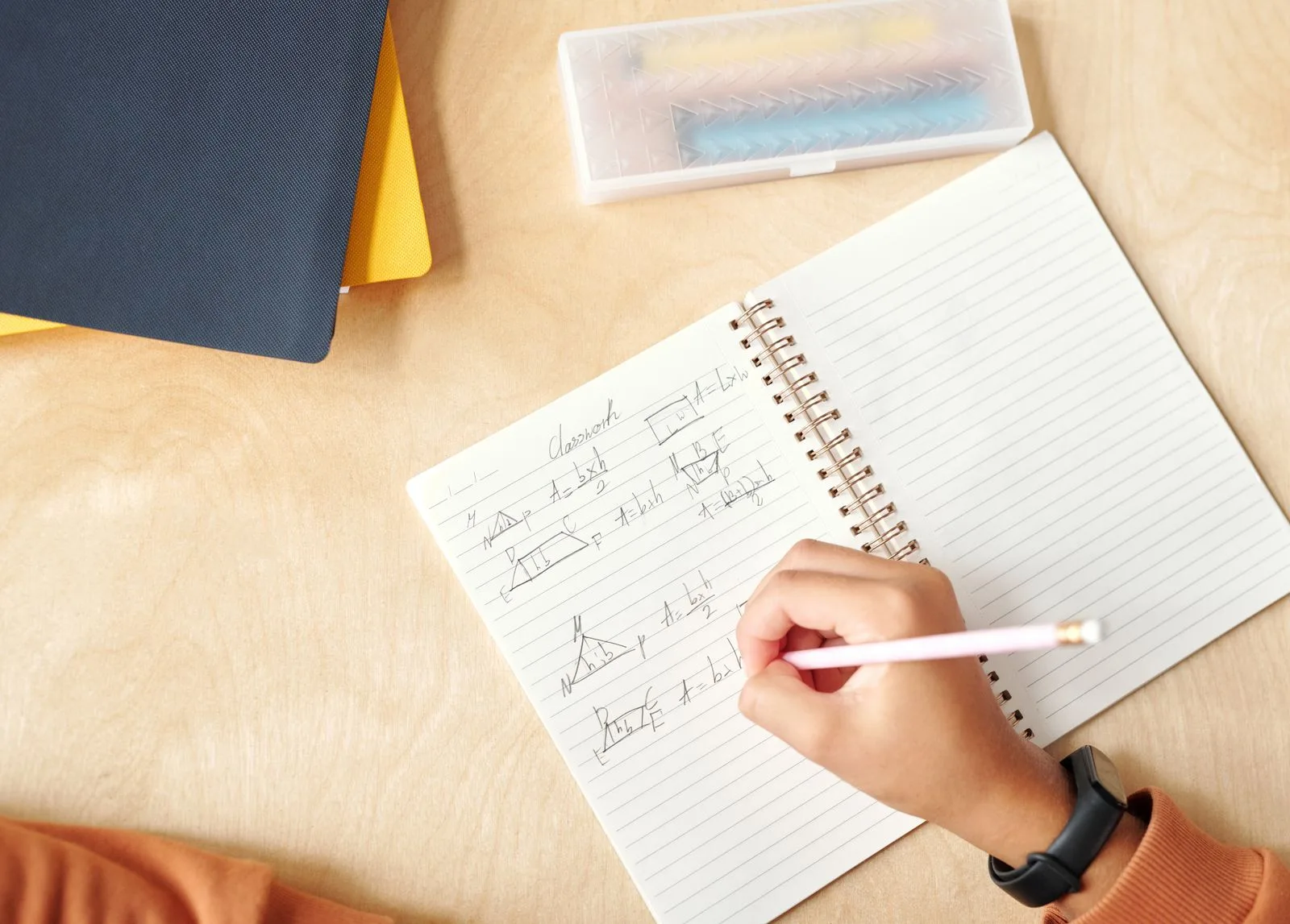 A learner working through geometry independently in a notebook